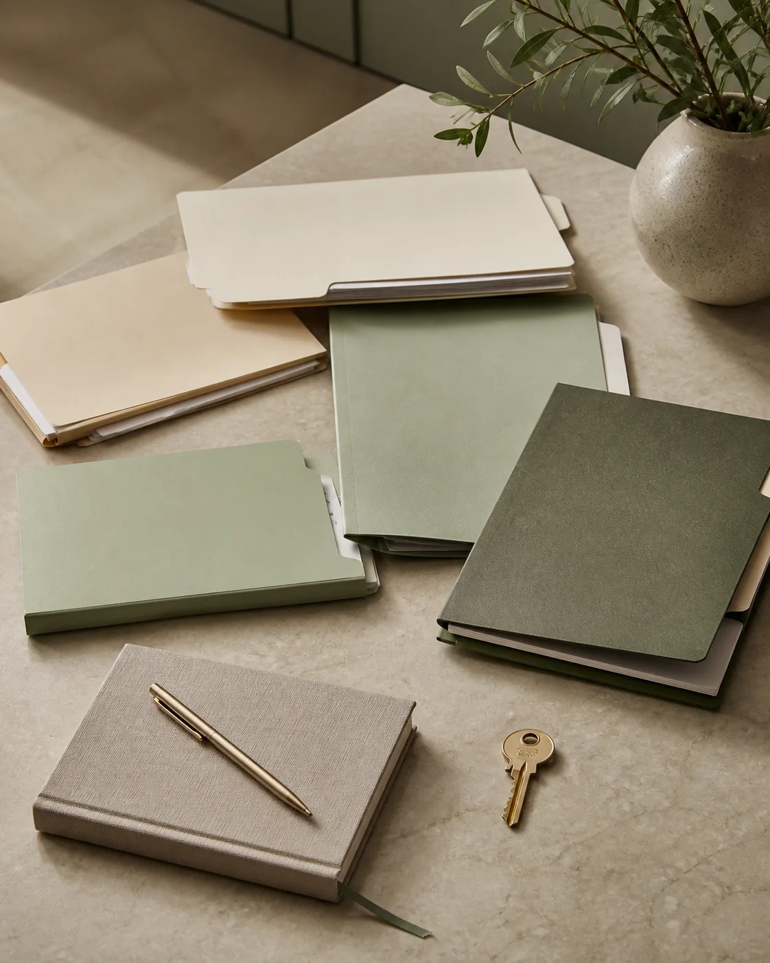 Distinct income folders, notebook and house key on a quiet desk