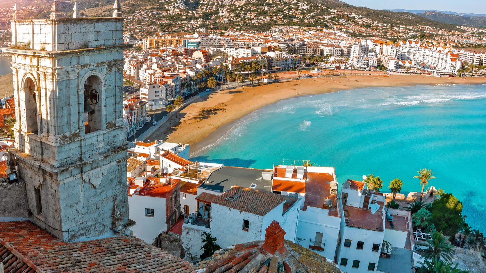 A Spanish coastal town beside a bright bay